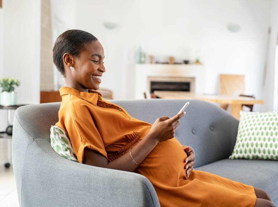 Pregnant african woman using smartphone at home