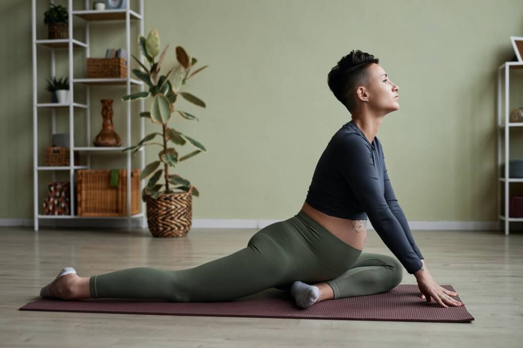 Pregnant young woman doing yoga at home stretching