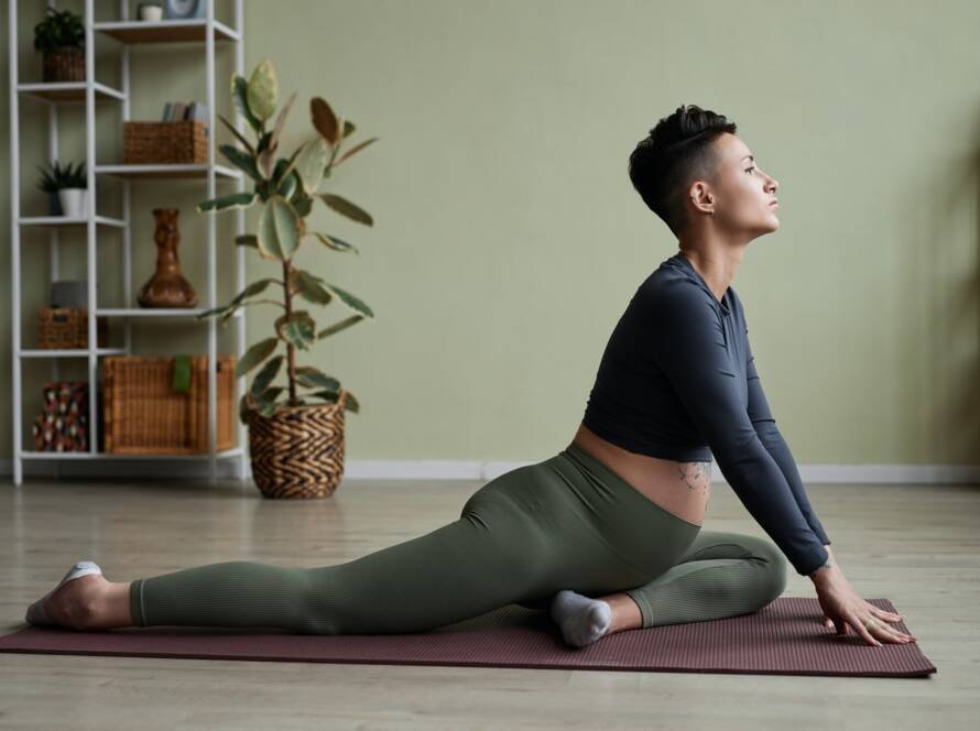 Pregnant young woman doing yoga at home stretching