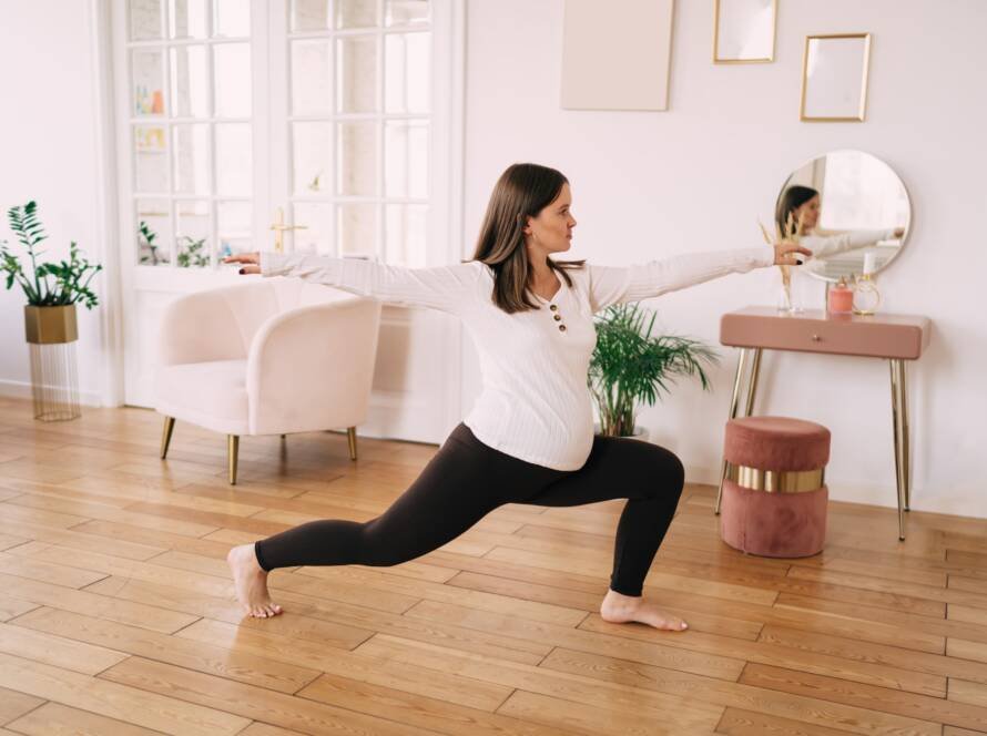 Slim pregnant woman doing yoga in living room