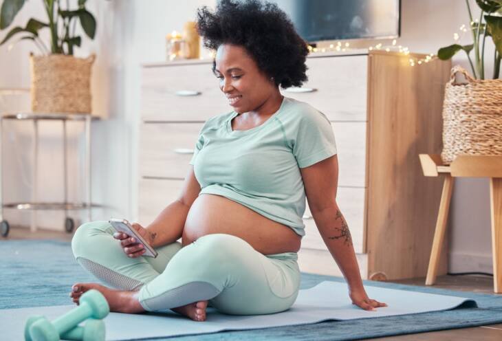 Yoga, pregnant and black woman with phone in home for social media and texting on workout break. Pr