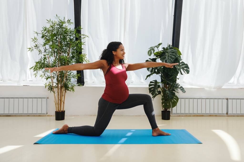 Young pregnant woman practicing yoga at home